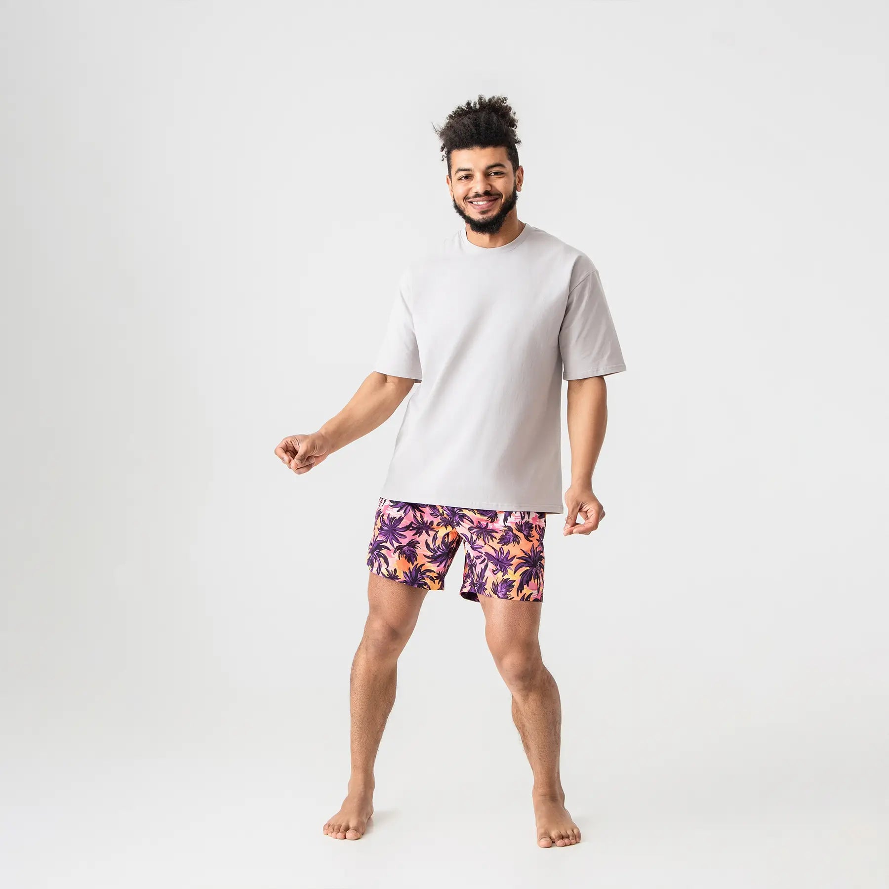 Man’s SET tropical palm print swim shorts in orange and purple, lightweight beachwear with gray T-shirt, model front view