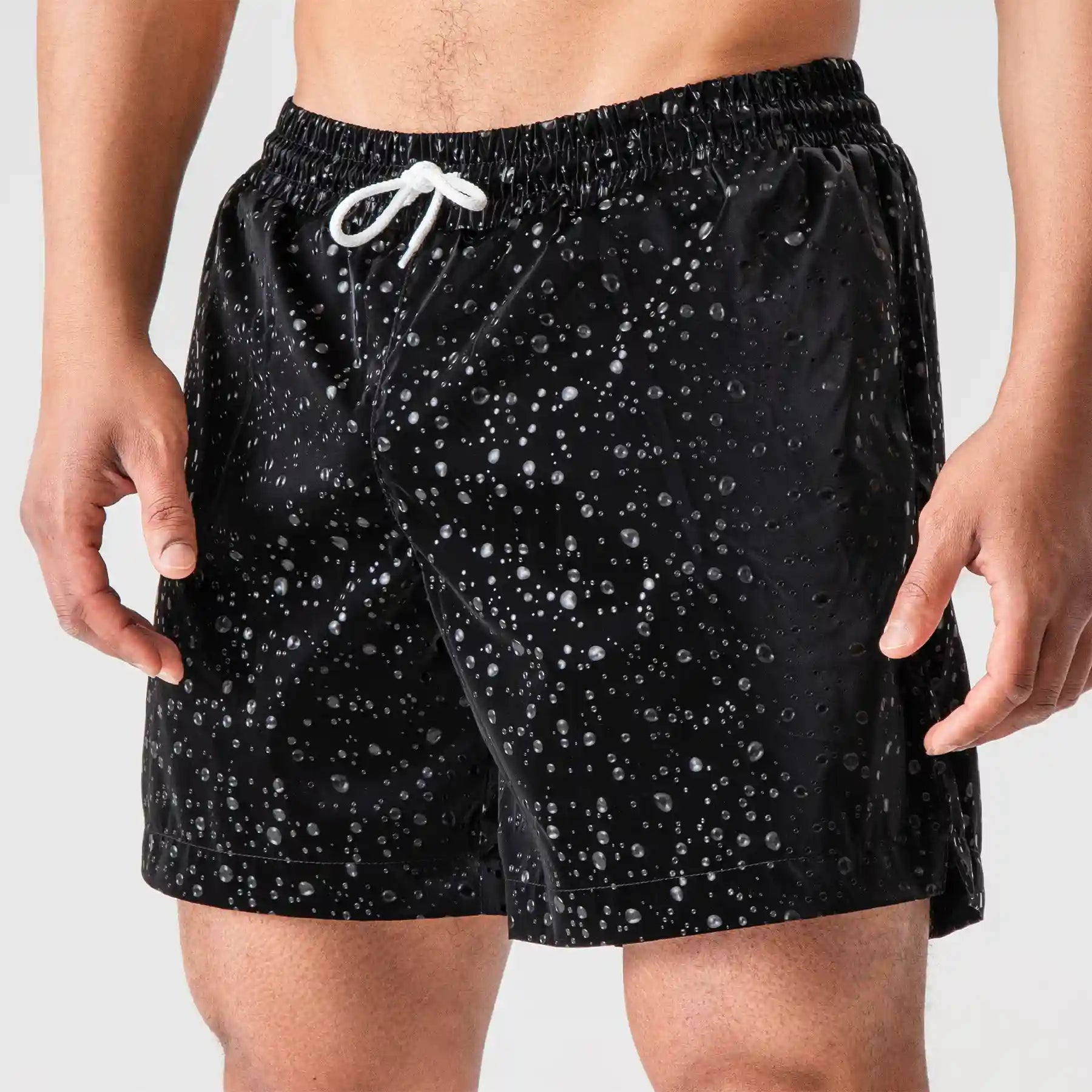 Man’s SET black swim shorts with white drawstring, water drop print, breathable swimwear, close-up front view