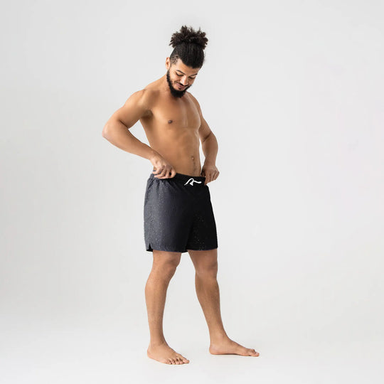 Man’s SET black swim shorts with white drawstring and water drop print, lightweight quick-dry fabric, model side view