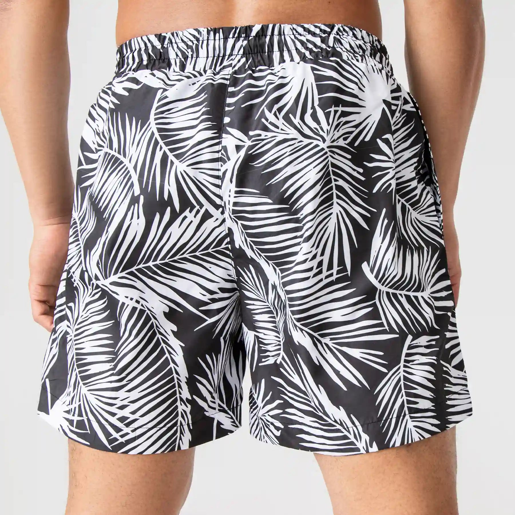 Men's tropical black swim shorts with white palm leaf print by Man’s SET, lightweight summer swimwear, back view